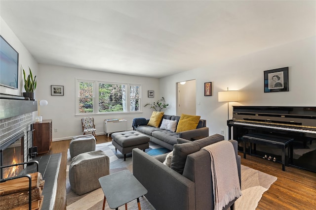 living room featuring baseboards, a brick fireplace, and wood finished floors