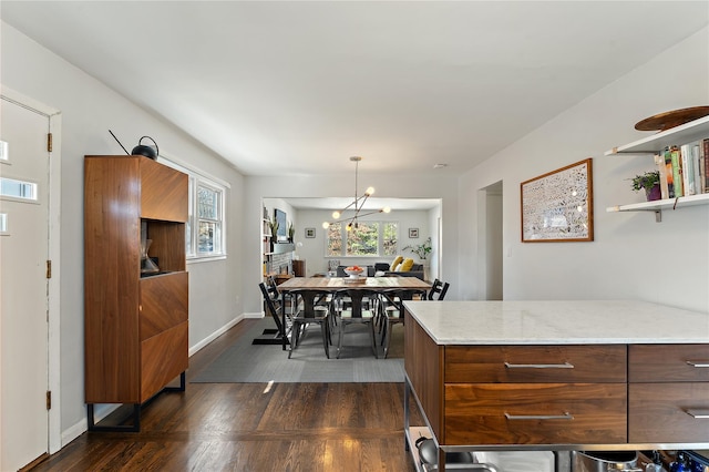 dining room featuring dark wood-type flooring, baseboards, and a chandelier