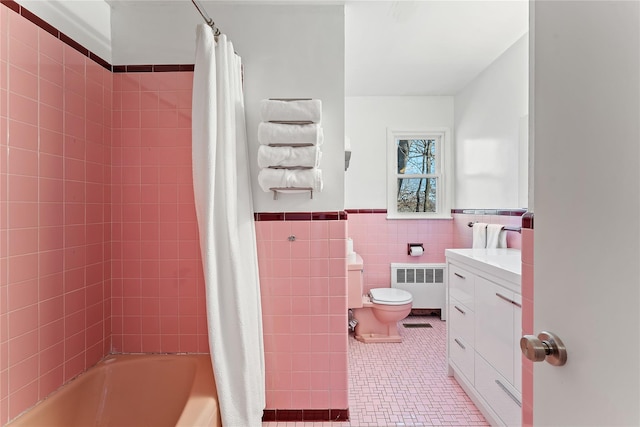 full bathroom with a wainscoted wall, radiator heating unit, tile walls, toilet, and tile patterned floors