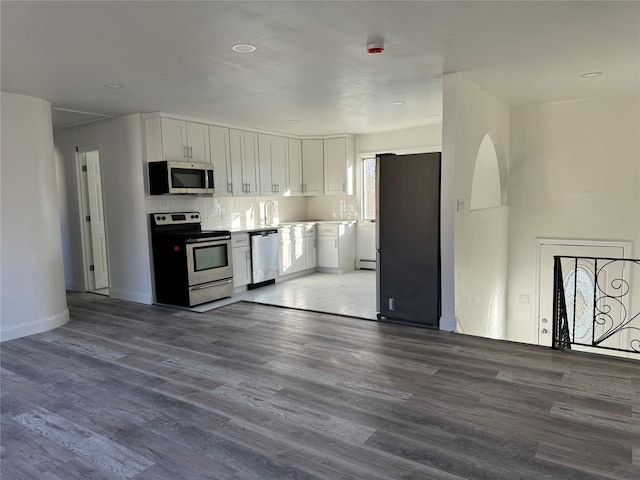 kitchen with sink, white cabinetry, tasteful backsplash, appliances with stainless steel finishes, and hardwood / wood-style floors