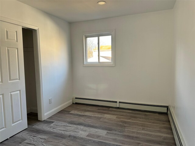 spare room featuring a baseboard heating unit and hardwood / wood-style floors