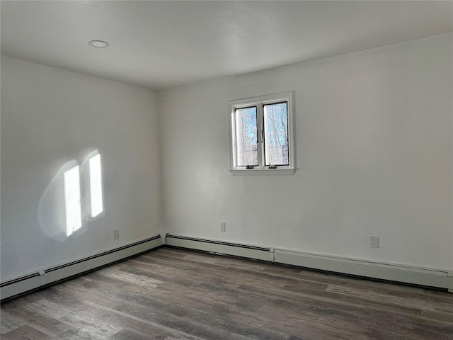 unfurnished room with a baseboard heating unit and dark hardwood / wood-style floors