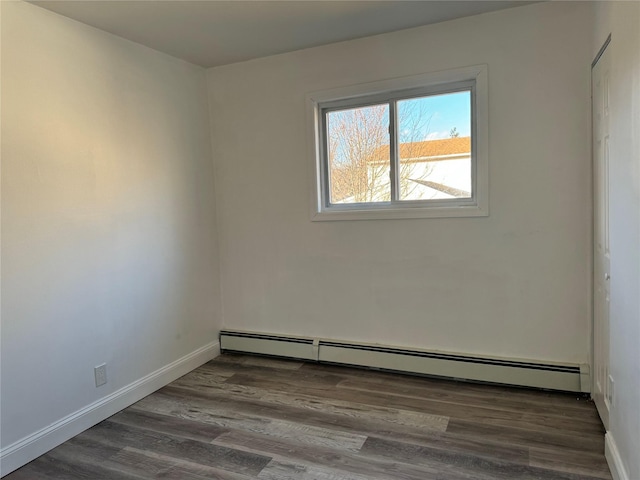 spare room featuring dark wood-type flooring and a baseboard radiator