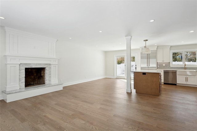 kitchen with appliances with stainless steel finishes, a center island, decorative light fixtures, a fireplace, and white cabinets