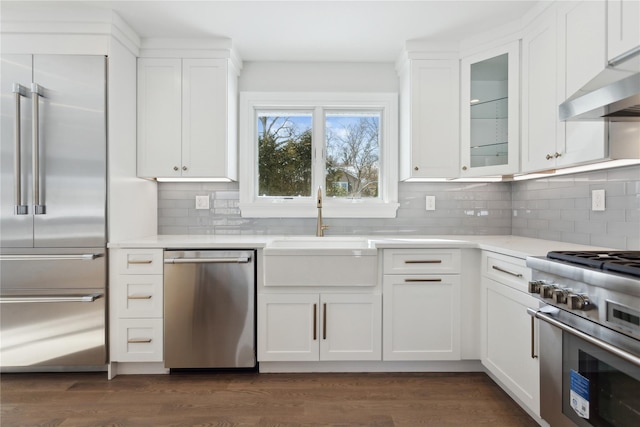 kitchen with sink, white cabinets, high quality appliances, and dark hardwood / wood-style flooring