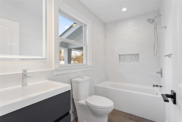 full bathroom featuring vanity, tile walls, toilet, and tiled shower / bath