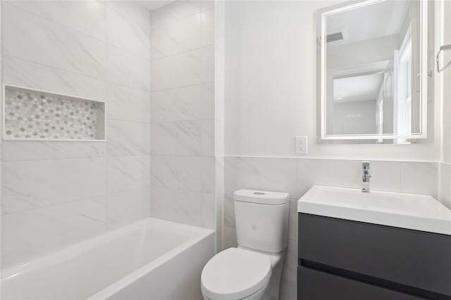 full bathroom featuring toilet, tile walls, tiled shower / bath combo, and vanity