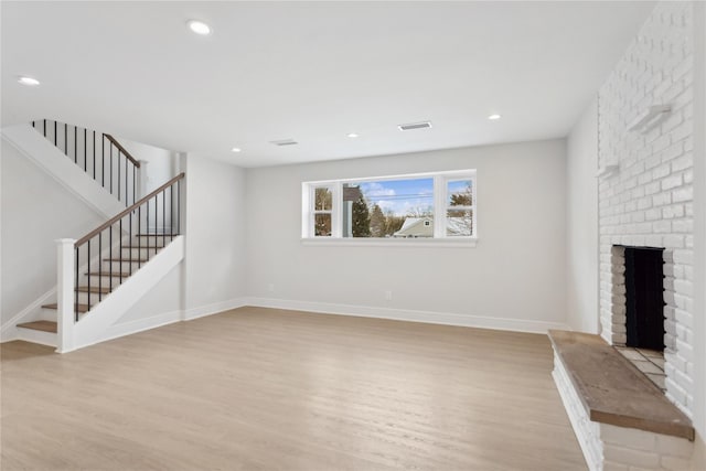 unfurnished living room featuring a brick fireplace and light wood-type flooring