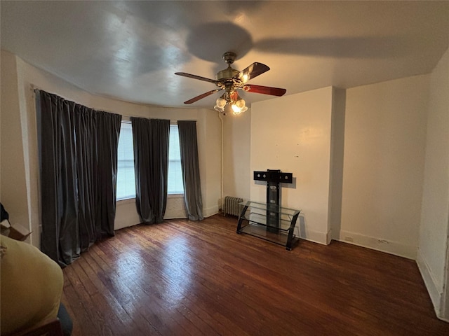 empty room with dark wood-type flooring, radiator heating unit, and ceiling fan