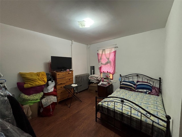 bedroom with dark wood-type flooring and radiator heating unit