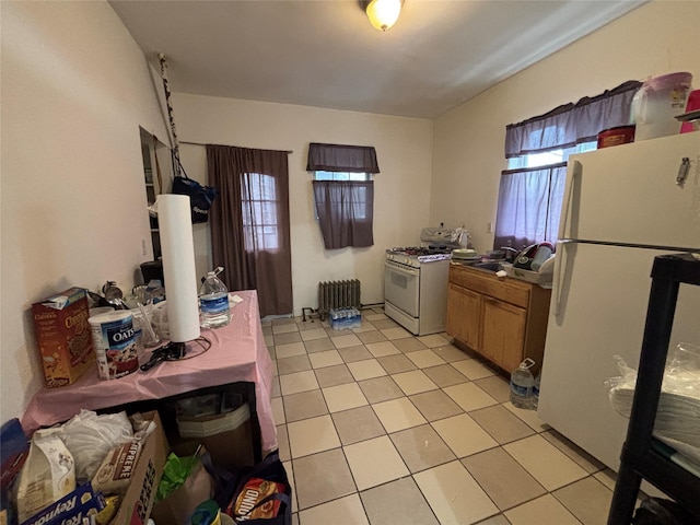 kitchen featuring light tile patterned flooring, radiator, sink, and white appliances