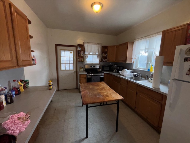 kitchen with sink, stainless steel range, and white fridge