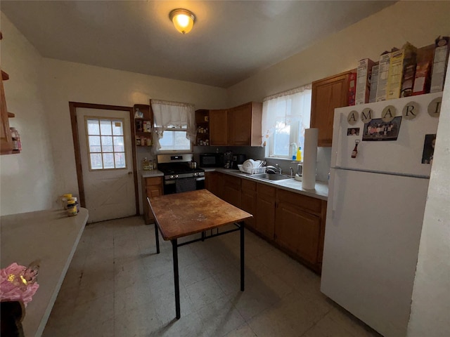 kitchen featuring white refrigerator, plenty of natural light, sink, and stainless steel electric range