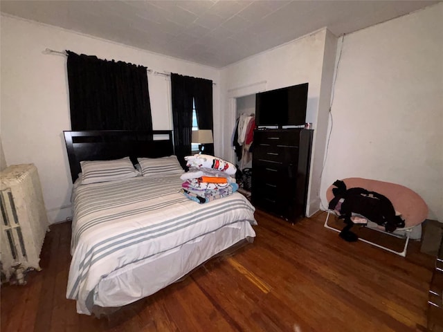 bedroom with radiator heating unit and dark hardwood / wood-style flooring