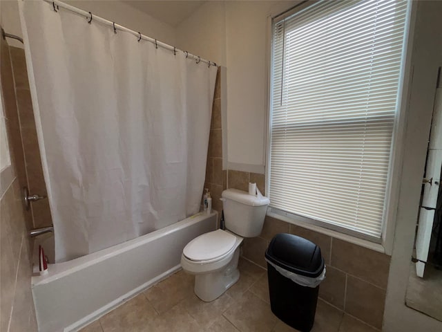 bathroom featuring tile walls, shower / tub combo, tile patterned floors, and toilet