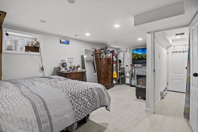 bedroom featuring a closet, a baseboard heating unit, light wood-type flooring, and a spacious closet