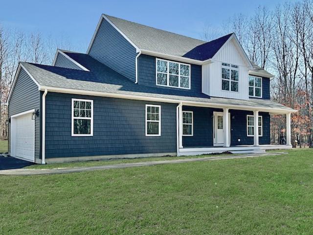 view of front of house featuring a garage, covered porch, and a front yard