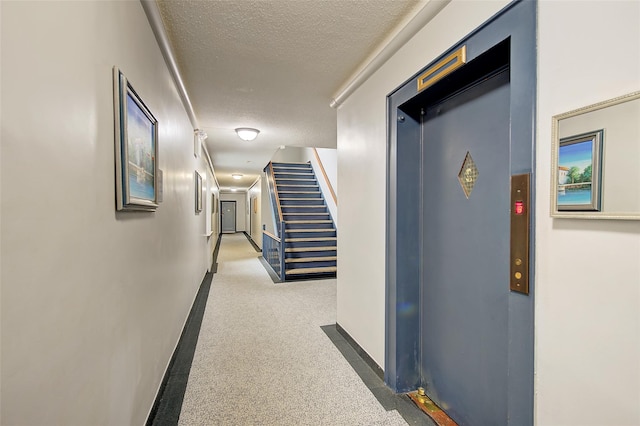 corridor with carpet floors, elevator, and a textured ceiling