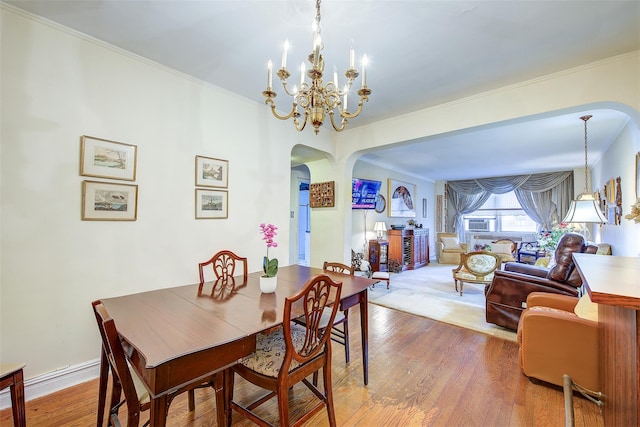 dining space with hardwood / wood-style flooring, crown molding, and a notable chandelier