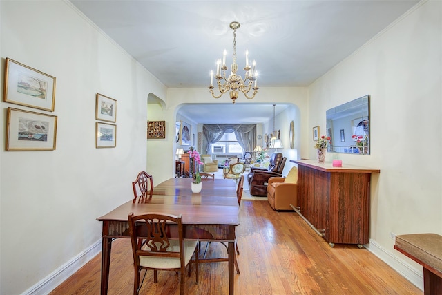 dining area with an inviting chandelier, crown molding, and light hardwood / wood-style floors