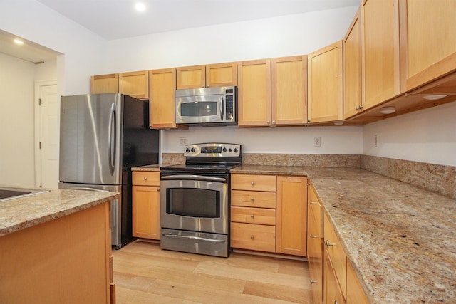 kitchen with light brown cabinets, light stone countertops, light hardwood / wood-style floors, and appliances with stainless steel finishes