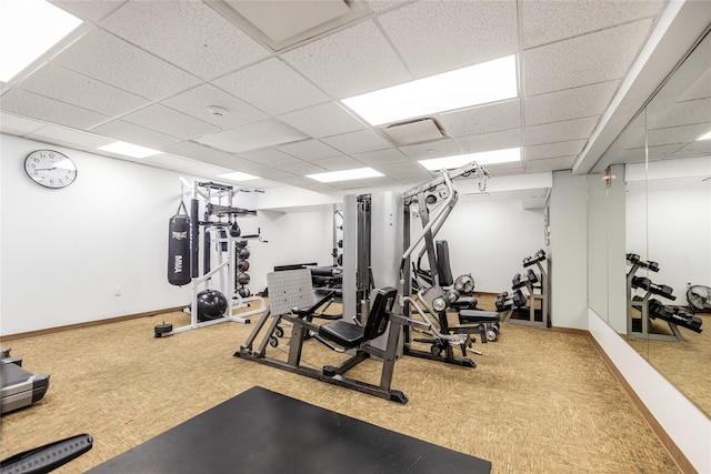 exercise room with a paneled ceiling and carpet flooring