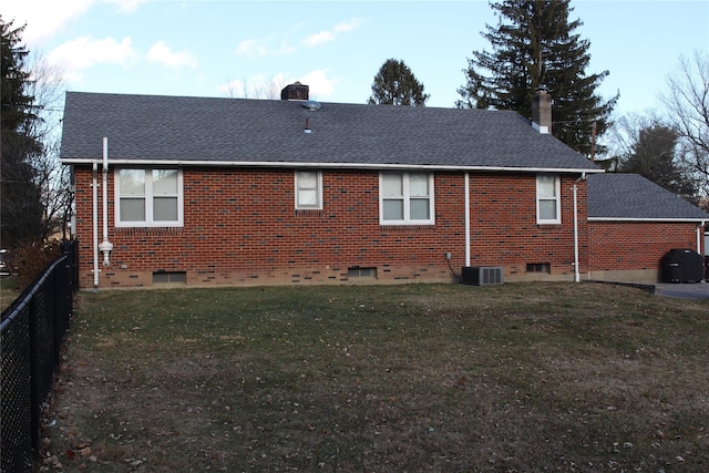 rear view of house with central AC and a lawn