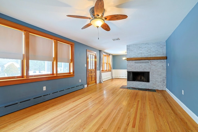 unfurnished living room with a baseboard heating unit, light hardwood / wood-style floors, a brick fireplace, and ceiling fan