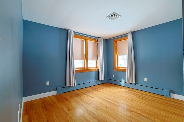 unfurnished room with a baseboard heating unit and light wood-type flooring