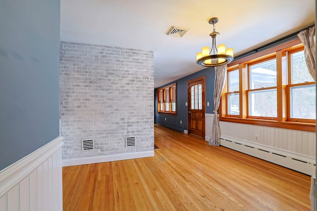 unfurnished room with baseboard heating, brick wall, and light hardwood / wood-style flooring