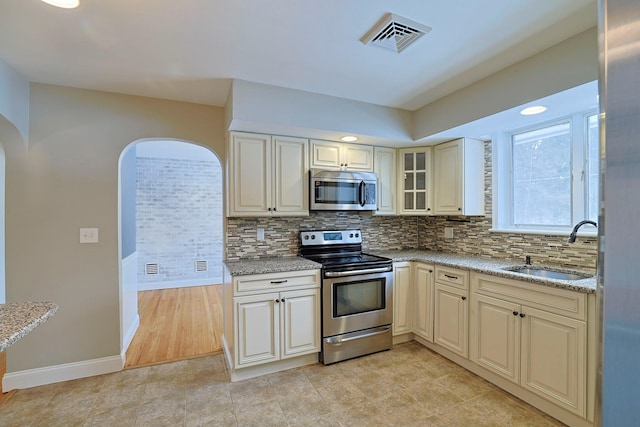 kitchen featuring stainless steel appliances, light stone countertops, sink, and decorative backsplash