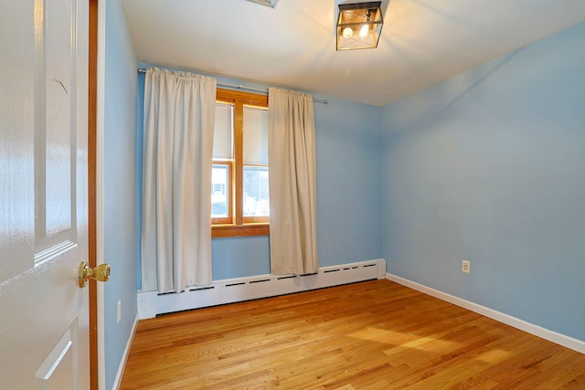 unfurnished room with a baseboard radiator and light hardwood / wood-style floors