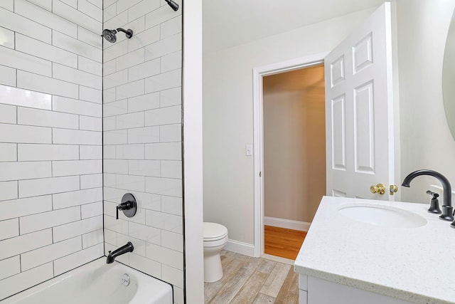 full bathroom featuring hardwood / wood-style flooring, vanity, tiled shower / bath combo, and toilet