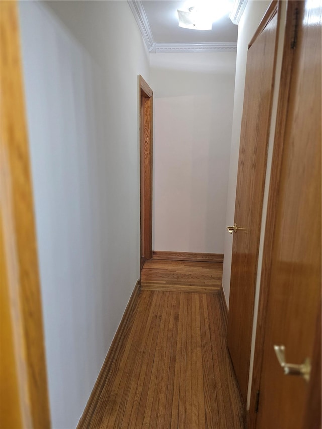 hallway with ornamental molding, hardwood / wood-style flooring, and baseboards