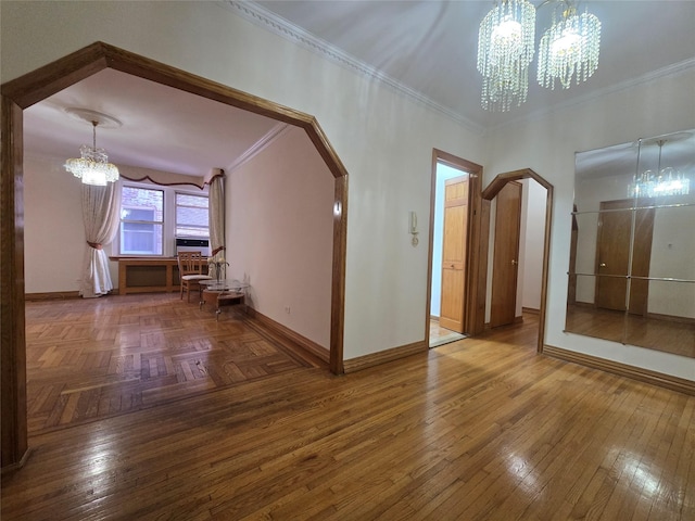 interior space with baseboards, arched walkways, a notable chandelier, and ornamental molding
