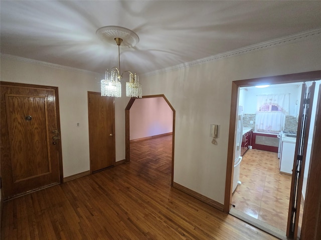 interior space with ornamental molding, arched walkways, a notable chandelier, and wood finished floors