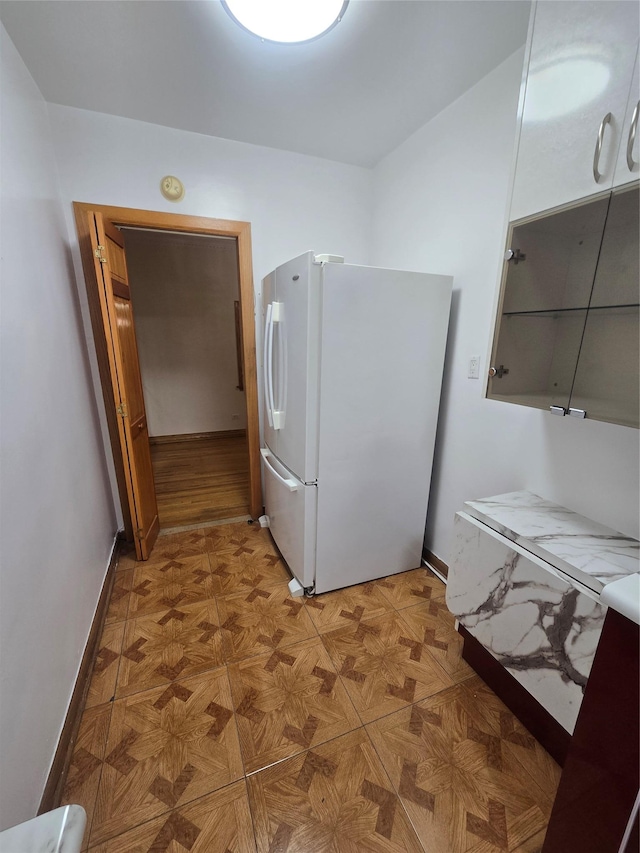 kitchen featuring baseboards and freestanding refrigerator
