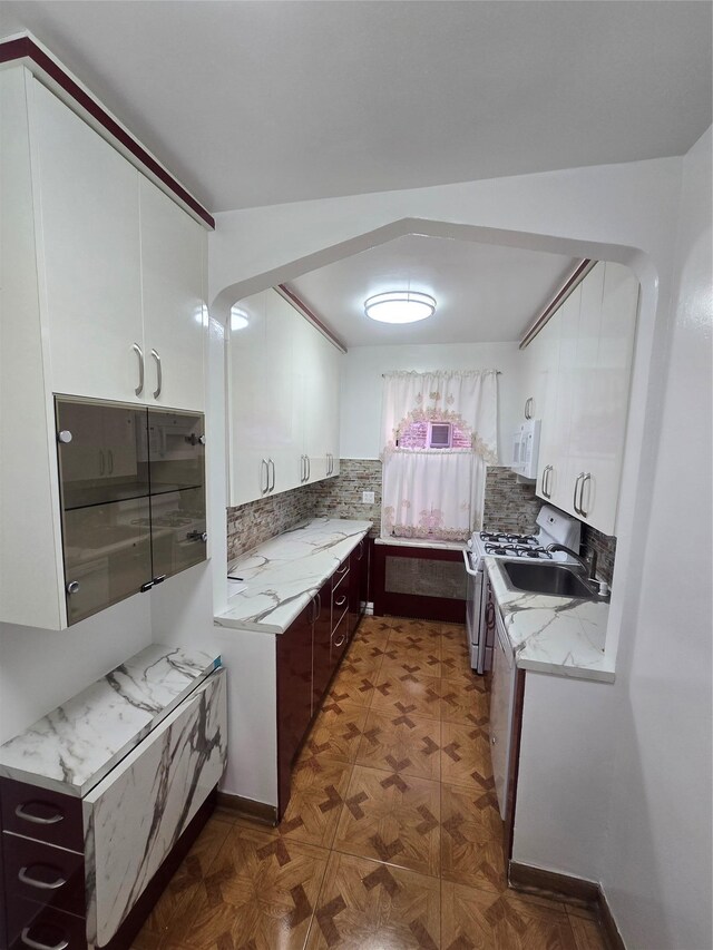 kitchen featuring decorative backsplash, white cabinets, a sink, light stone countertops, and white appliances