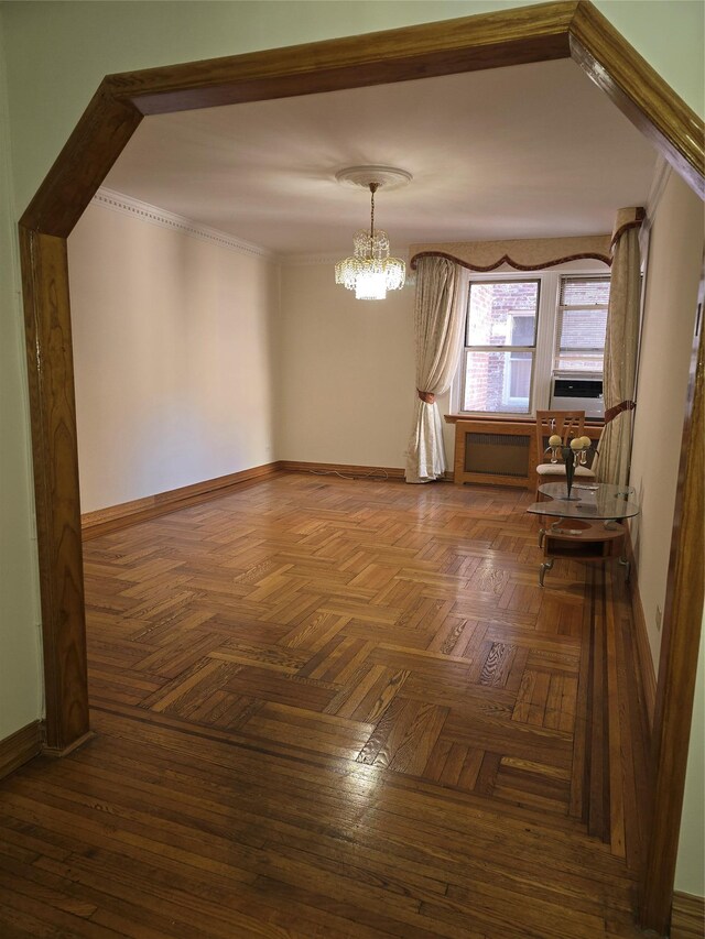 empty room featuring ornamental molding, a notable chandelier, and baseboards