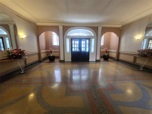 foyer with crown molding, baseboards, and decorative columns