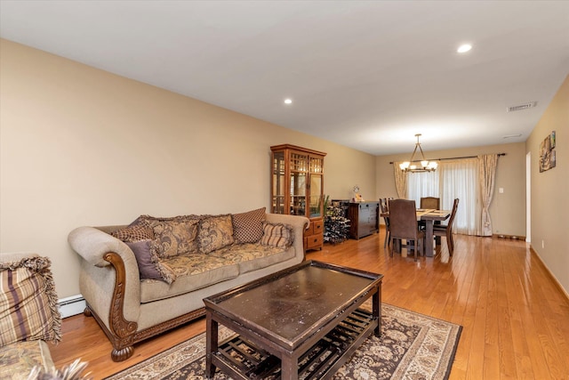 living room with an inviting chandelier, light wood-type flooring, and baseboard heating