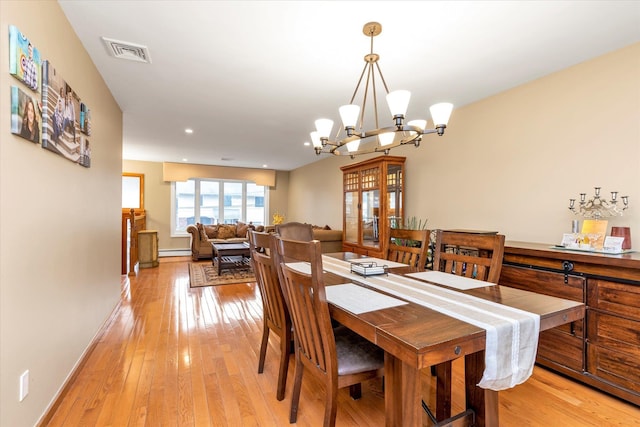 dining room with baseboard heating, a chandelier, and light wood-type flooring