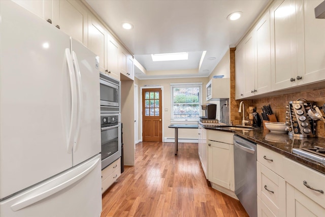 kitchen with stainless steel appliances, white cabinetry, and sink