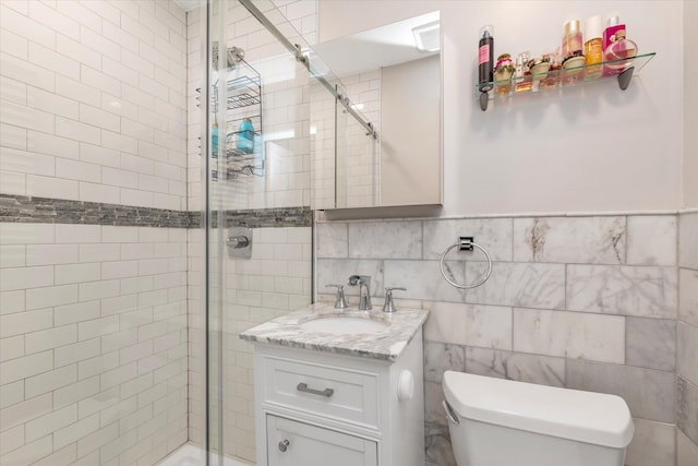 bathroom featuring vanity, toilet, a shower with door, and tile walls