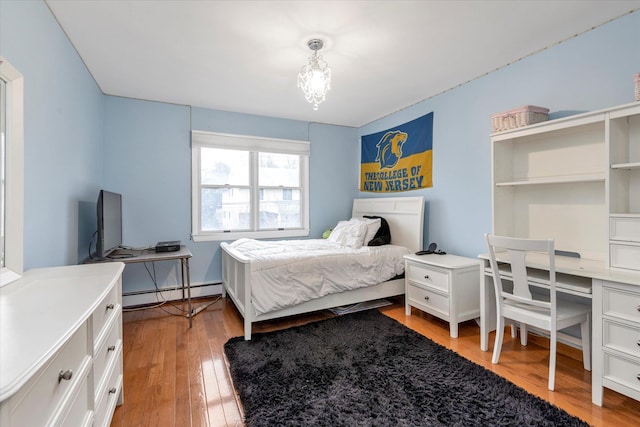 bedroom featuring a baseboard radiator, hardwood / wood-style floors, and a notable chandelier