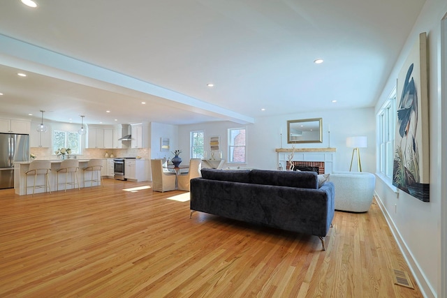 living room featuring a brick fireplace and light wood-type flooring