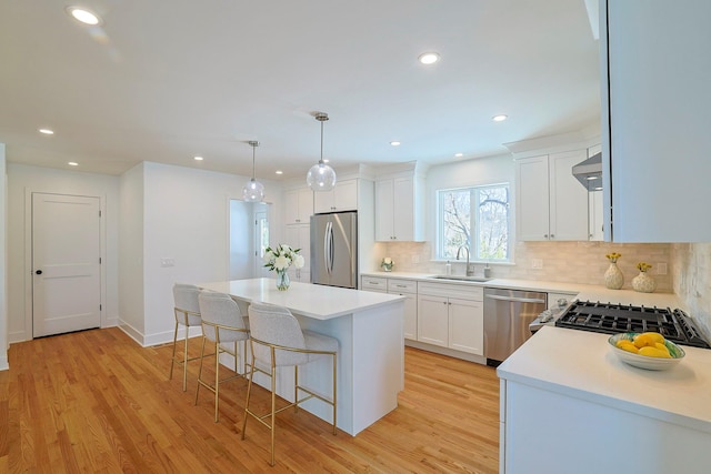 kitchen featuring white cabinetry, decorative light fixtures, a kitchen island, and appliances with stainless steel finishes