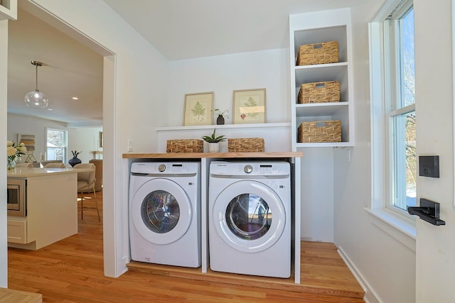 laundry area with light hardwood / wood-style flooring and washing machine and dryer