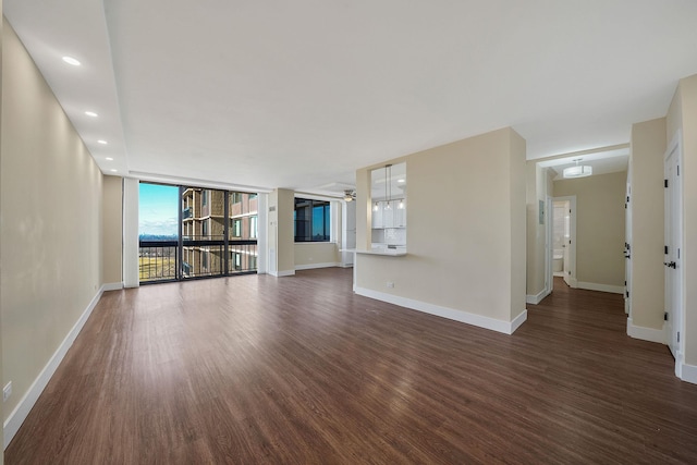 unfurnished living room with a wall of windows and dark hardwood / wood-style flooring