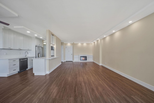 unfurnished living room featuring sink and dark hardwood / wood-style flooring